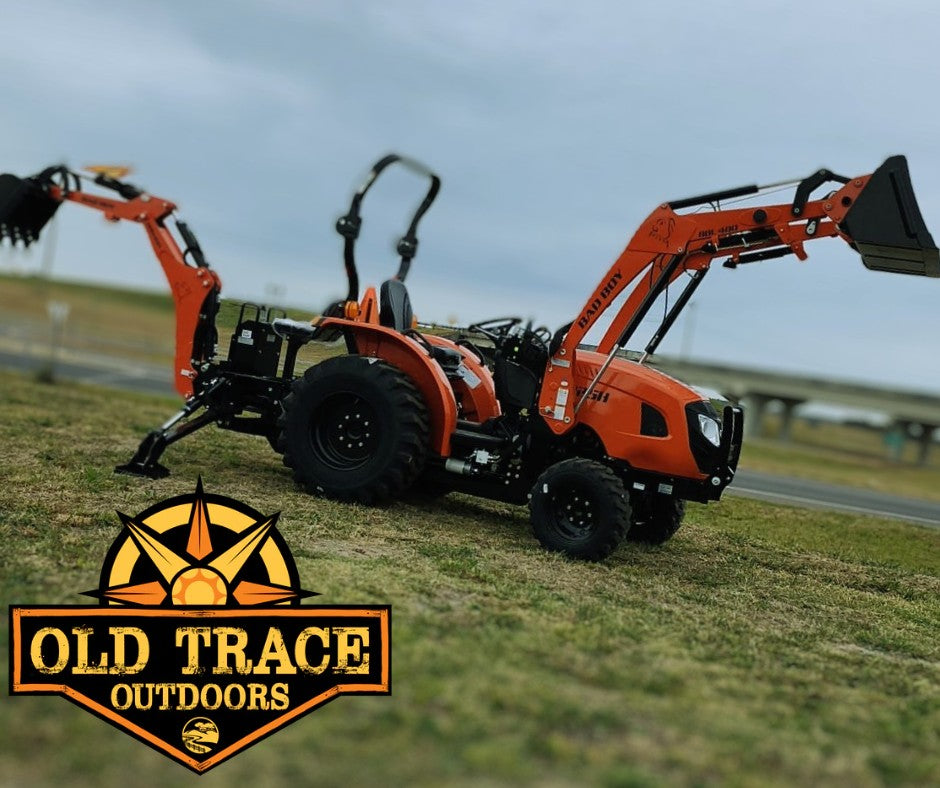 Orange Bad Boy tractor with a front loader and backhoe in a field
